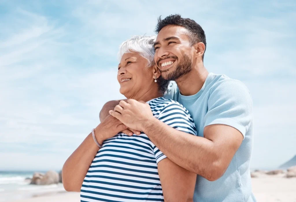 Old woman and her support worker hugging her from the back while smiling
