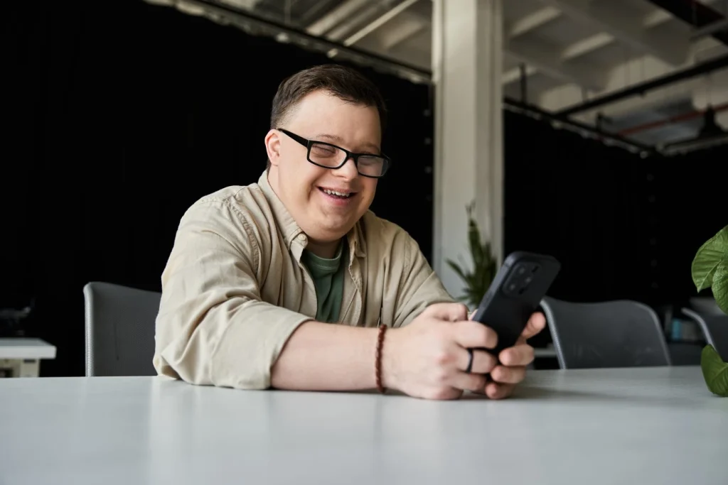 A disabled man smiling while looking at his phone